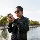 Jovem mulher em óculos de sol usando telefone celular — Fotografia de Stock