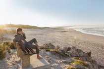 Mann entspannt sich auf Strandbank — Stockfoto