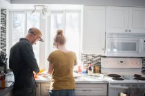 Mittleres erwachsenes Paar bereitet Essen in Küche zu — Stockfoto