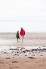 Madre e hija caminando hacia el mar - foto de stock