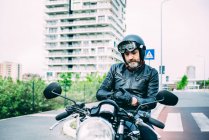 Älterer männlicher Motorradfahrer sitzt auf Motorrad und zieht Handschuhe an — Stockfoto