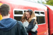Two female friends hugging at railway station, smiling — Stock Photo