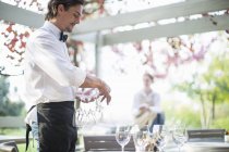 Kellner bereitet Weingläser auf Tisch im Terrassenrestaurant zu — Stockfoto