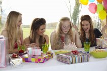 Adolescente chica soplando velas de cumpleaños con amigos - foto de stock