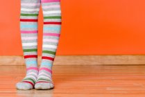 Girl child feet wearing striped tights — Stock Photo