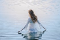 Вид сзади на молодую женщину, стоящую на волнистой поверхности озера — стоковое фото
