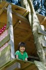 Усміхнений хлопчик сидить у будинку на дереві — стокове фото