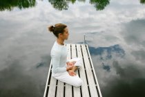Man meditating on wooden pier — Stock Photo