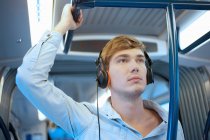 Jeune homme dans une voiture de train écoutant des écouteurs — Photo de stock