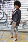 Portrait urbain d'une jeune blogueuse de mode aux cheveux afro par un mur de graffiti, New York, USA — Photo de stock