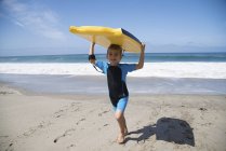 Ragazzo che corre sulla spiaggia e trasporta bodyboard, Laguna Beach, California, USA — Foto stock
