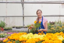 Взрослая женщина с цветами в садовом центре, улыбающаяся — стоковое фото