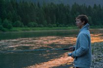 Adolescente ragazzo pesca nel fiume al tramonto, Washington, Stati Uniti d'America — Foto stock