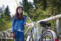 Ragazza adolescente guardando la sua bicicletta su strada rurale — Foto stock