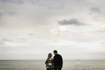 Young couple outdoors, beside sea, rear view — Stock Photo