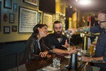 Bartender pouring cocktail for young couple in public house — Stock Photo