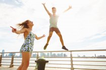 Young man jumping mid air on sunlit waterfront, New York, USA — Stock Photo