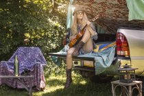 Giovane donna che gioca ukulele durante il campeggio in pick up boot — Foto stock