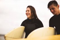 Amis marchant loin de la mer, portant des planches de surf — Photo de stock