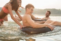 Friends having fun with inflatable ring in river — Stock Photo