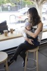 Madre seduta in un caffè con un giovane figlio — Foto stock