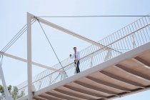 Homme d'affaires marchant sur un pont urbain — Photo de stock