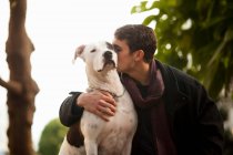 Чоловік цілує собаку на відкритому повітрі — стокове фото