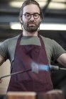 Hombre calentando hierro de marca con soplete en fábrica - foto de stock