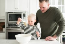 Father and son baking together, son mixing mixture — Stock Photo