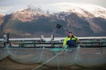 Travailleur dans une salmoniculture dans un lac rural — Photo de stock