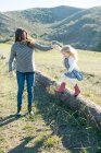 Mid adult woman holding daughter's hand while she jumps from log — Stock Photo