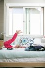 Ritratto di ragazza sdraiata sul letto con le gambe sollevate — Foto stock