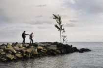 Jeune couple marchant sur des rochers au bord de la mer — Photo de stock