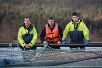 Workers on salmon farm in rural lake — Stock Photo