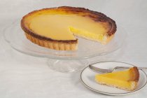 Lemon tart on cakestand and portion on plate — Stock Photo