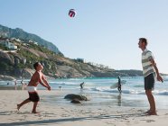 Père et fils jouant au ballon sur une plage — Photo de stock