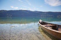 Ragazzo piegato in avanti dalla barca a remi e guardando nel lago, Kochel, Baviera, Germania — Foto stock