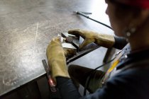 Über-die-Schulter-Ansicht einer Metallschmiedin, die Metall an Werkstattbank ausrichtet — Stockfoto
