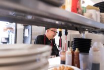 Vista attraverso scaffali di chef che lavorano in cucina commerciale — Foto stock