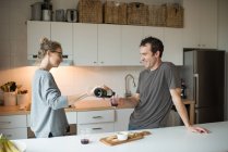 Couple pouring red wine in kitchen — Stock Photo