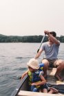 Молодой человек и дочь плывут через озеро на лодке — стоковое фото
