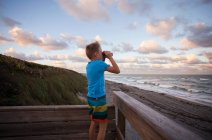 Garçon à la plage regardant la vue à travers des jumelles, Blowing Rocks Preserve, Jupiter, Floride, États-Unis — Photo de stock