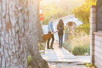 Young couple walking outdoors, young man holding guitar — Stock Photo