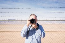 Fotografo di fronte alla recinzione di filo spinato nel deserto scattare foto, California, Stati Uniti — Foto stock