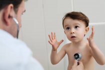 Doctor using stethoscope to check little boy — Stock Photo