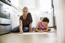 Mutter und Tochter sitzen auf dem Küchenboden und zeichnen — Stockfoto