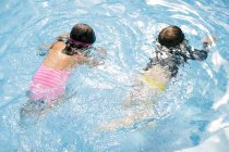 Vista aérea de niño y niña nadando en piscina al aire libre - foto de stock