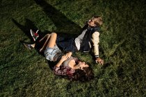 Casal deitado na grama à noite, ângulo alto — Fotografia de Stock