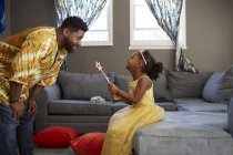 Uomo che gioca con la figlia in costume da fata in soggiorno — Foto stock