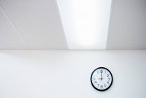 Horloge sur mur de bureau blanc — Photo de stock